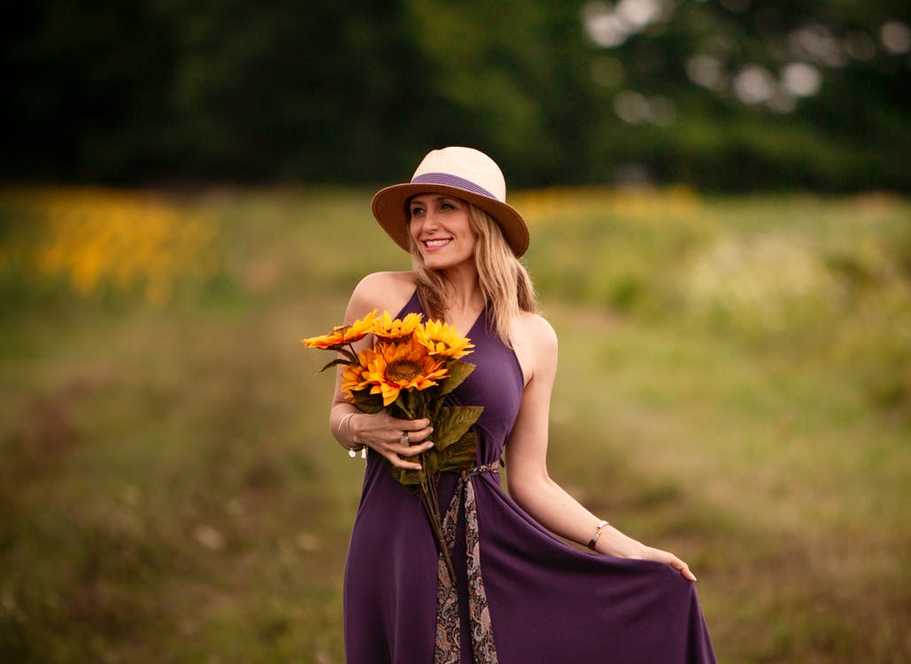 Photo of Smiling Woman in Purple Dress Holding Sunflower Bouquet